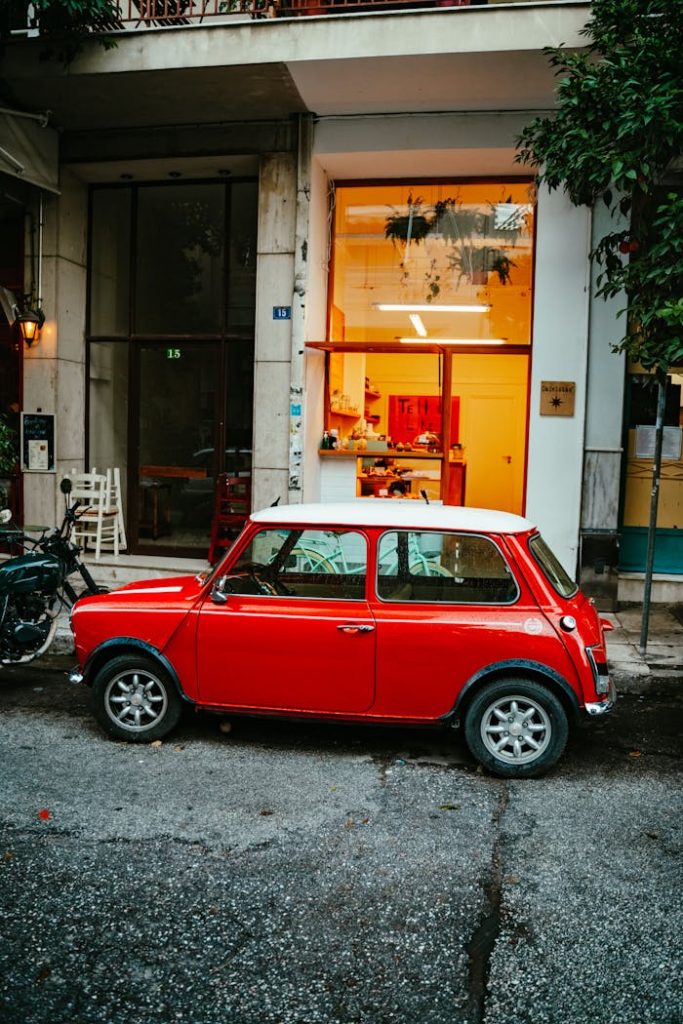 A vibrant red classic car parked on a street in Athens, Greece, outside a café.